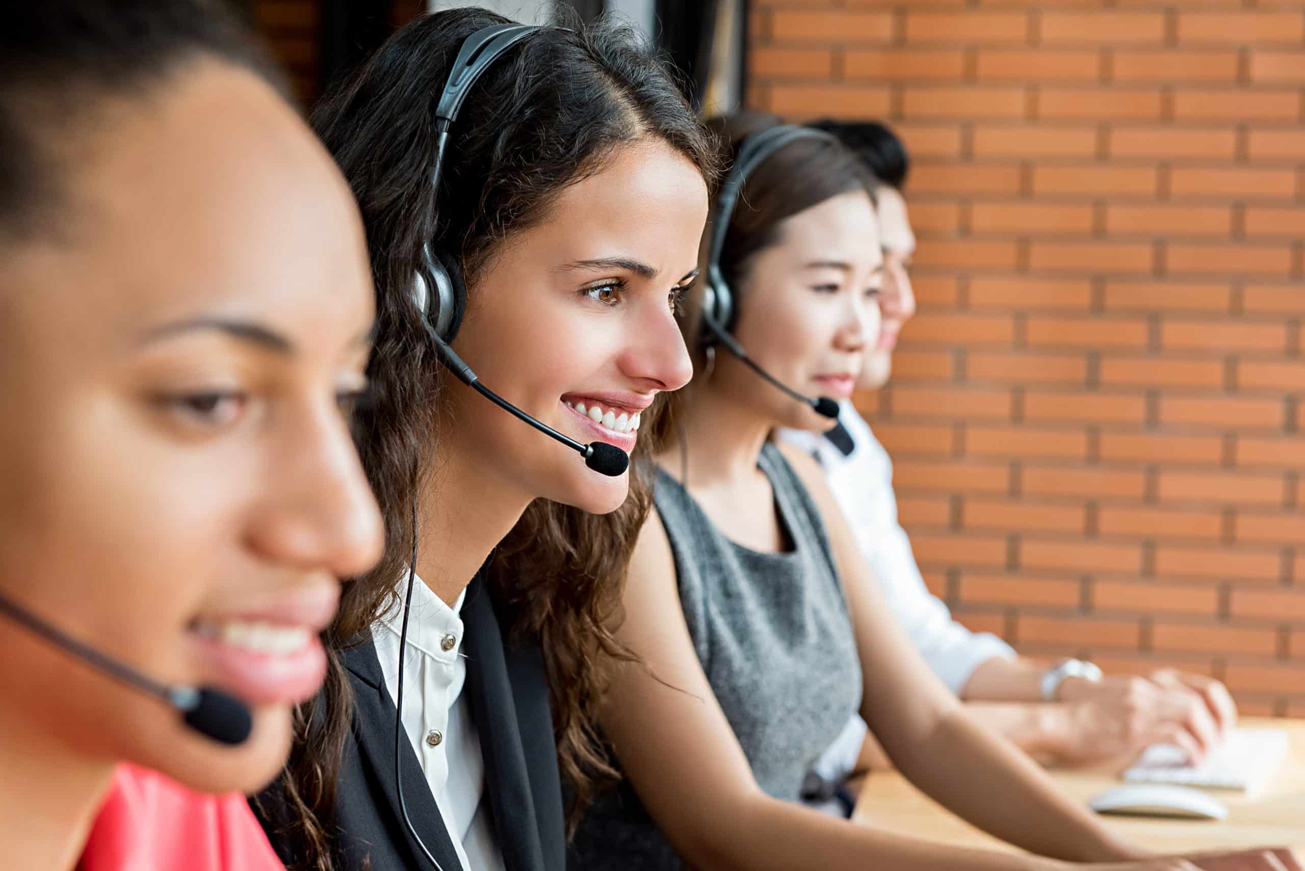 Smiling multiethnic telemarketing customer service agents, call Contact Us support at Moon Security Services Inc.